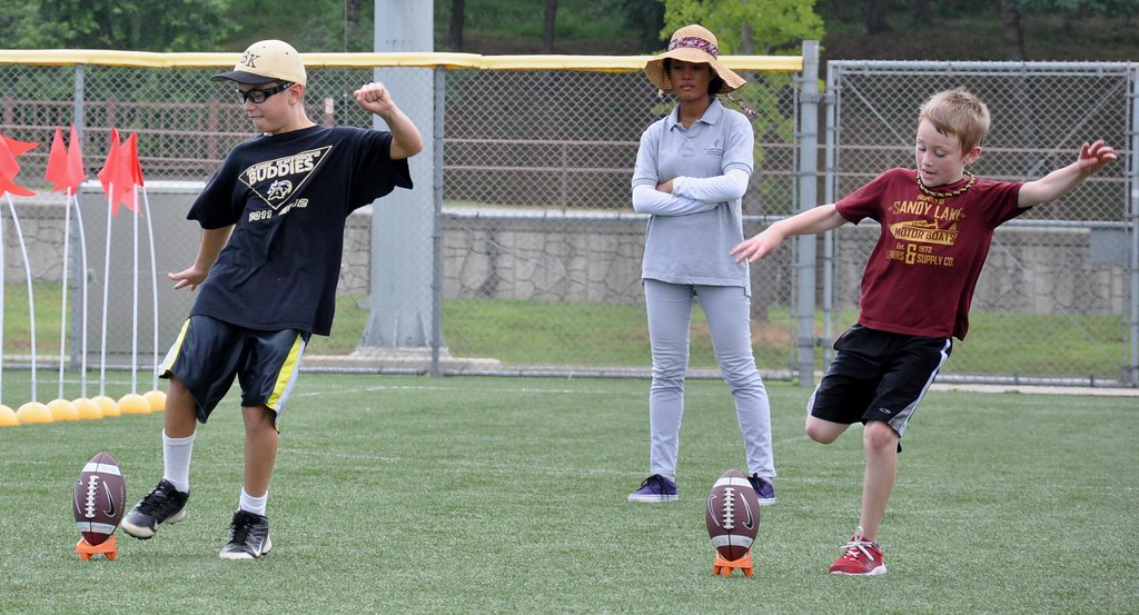 Kids running a flag football drill at a youth clinic